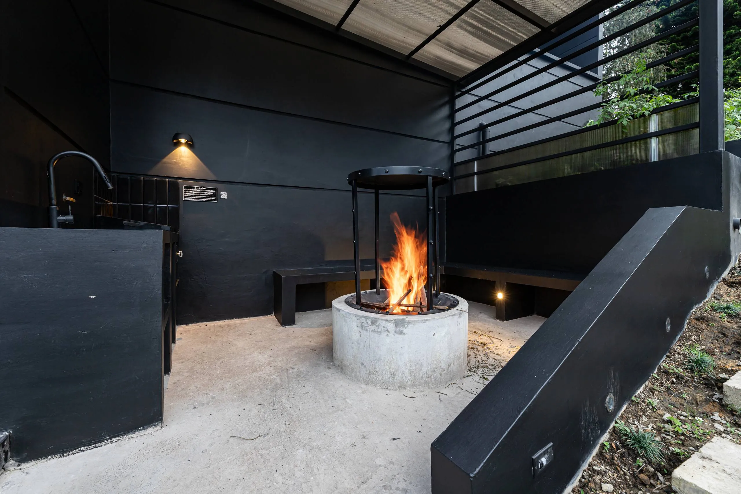 The covered outdoor fireplace, lit against dark timber walls