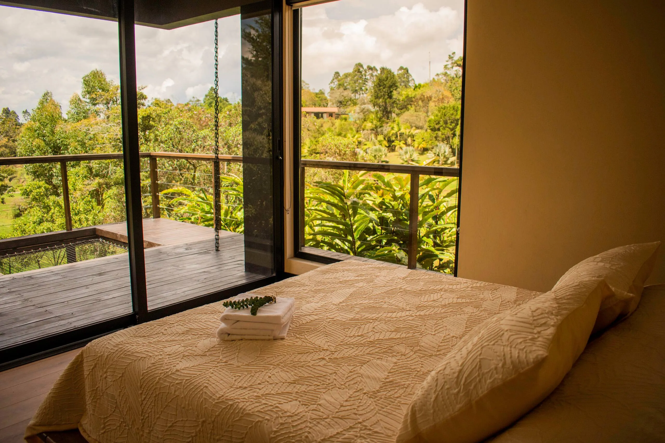 A bedroom filled with golden afternoon light, greenery framed in the window